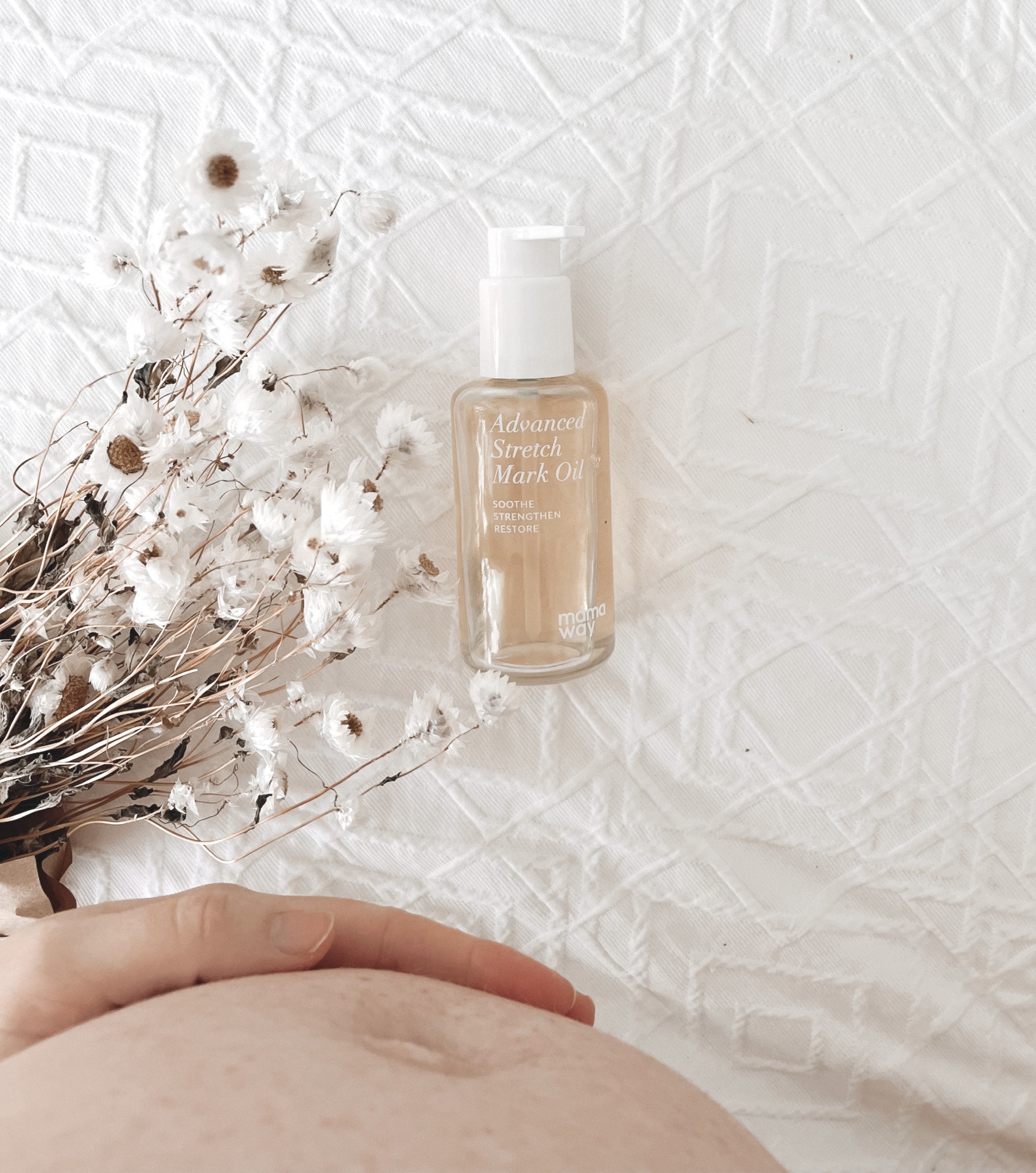 Mamaway Advanced Stretch Mark Oil beside dried flowers