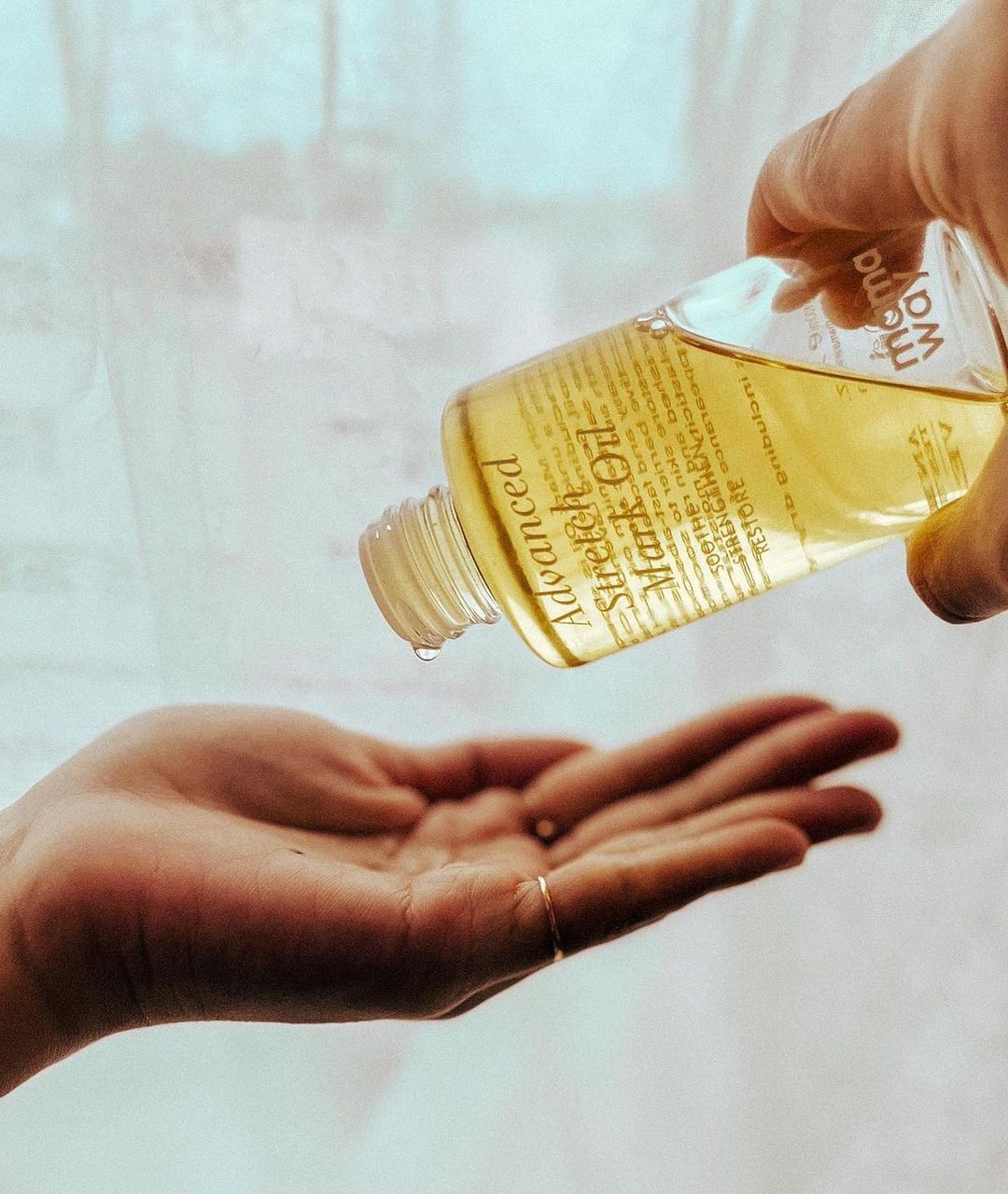 Chloe pouring Mamaway Advanced Stretch Mark Oil into her hand